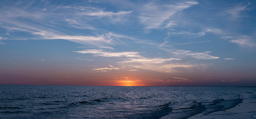 Serene Sunset Over Ocean with Wispy Clouds and Calm Waves