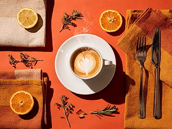 Flat Lay of Latte with Citrus Slices and Herbs on Orange Background
