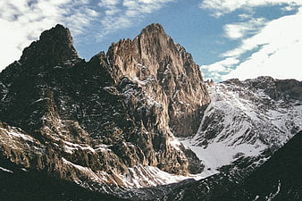 Dramatic jagged mountain peak with snow and clouds