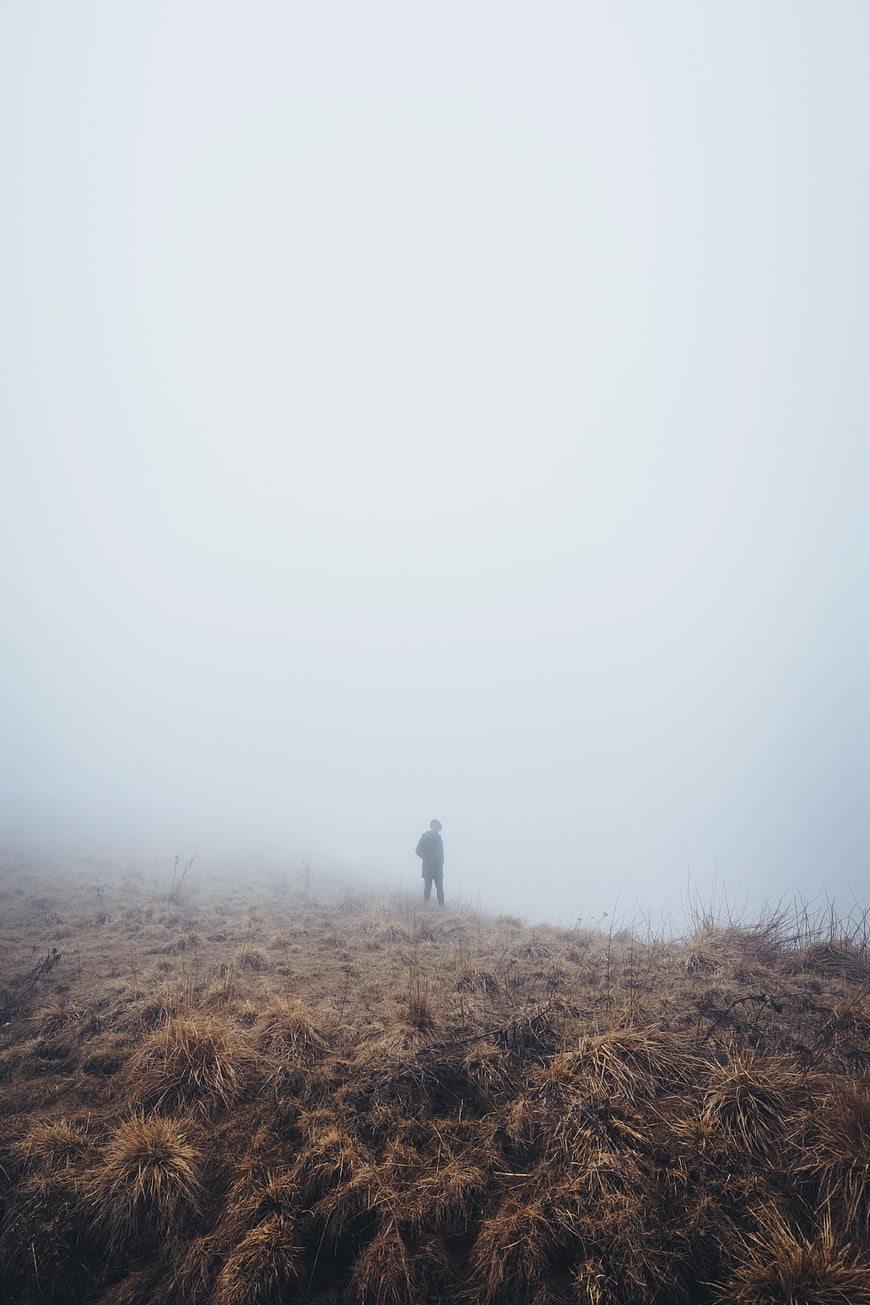 Lone Hiker Standing in Foggy Highland Grass