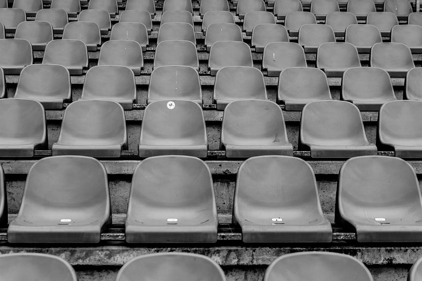 Rows of empty stadium seats in black and white