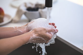 Close-up of hands washing with soap and water under faucet