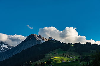 Alpine mountain landscape with green meadows and blue sky