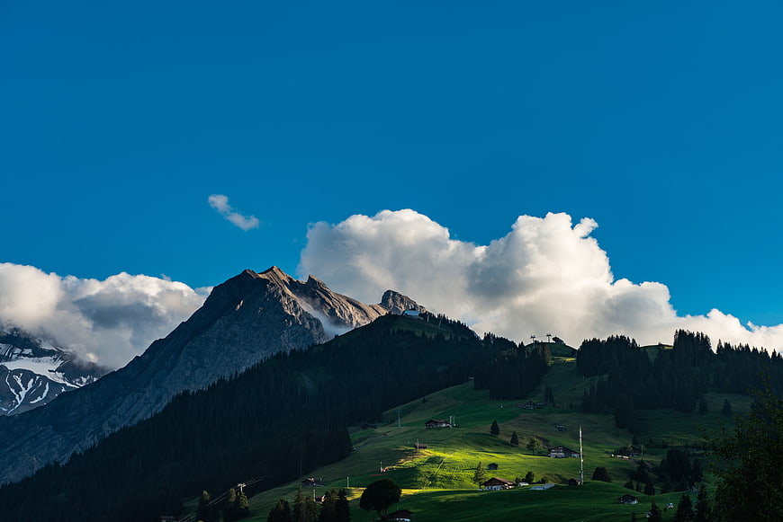 Alpine mountain landscape with green meadows and blue sky
