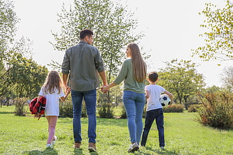 Happy family walking together in a sunny park with soccer ball