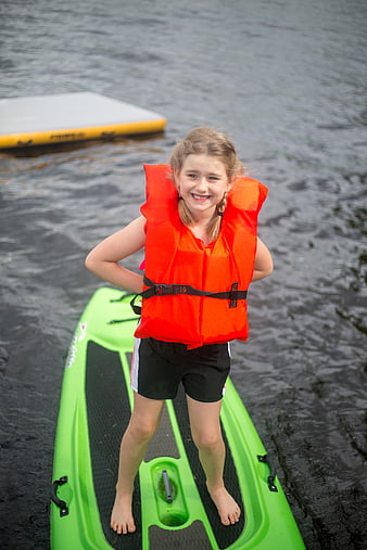 Happy Girl in Orange Life Jacket on Green Kayak