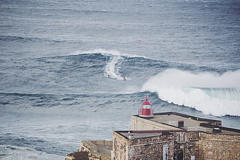 Surfers riding waves near historic lighthouse fortification