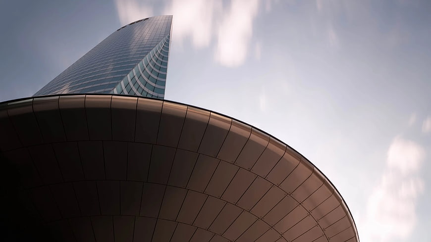 Low angle view of modern glass skyscraper and curved architecture