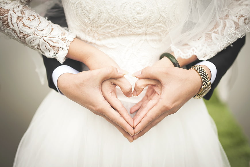 Wedding couple hands forming heart shape close up