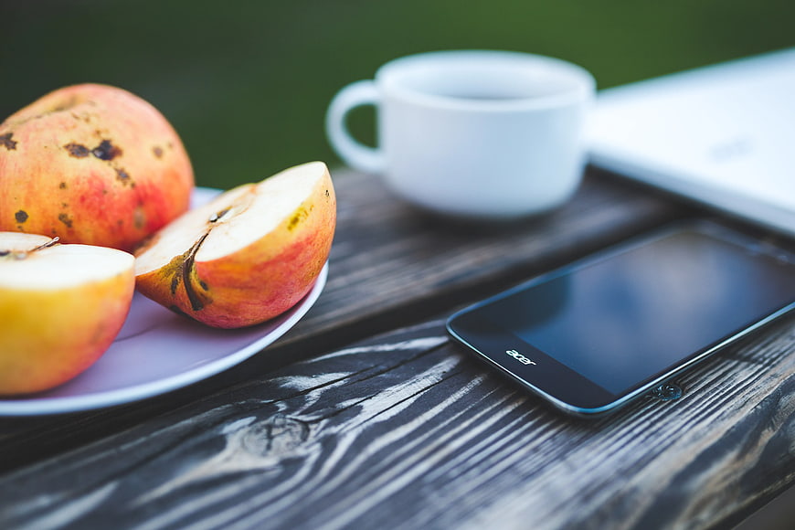 Fresh apples, coffee, and smartphone on rustic wooden table