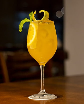 Refreshing yellow cocktail with lemon and mint garnish