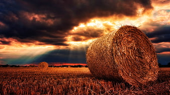 Dramatic Hay Bale in Harvested Field at Sunset