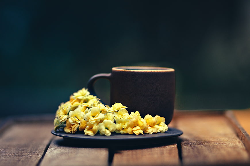 Ceramic coffee cup with yellow flowers on wooden table
