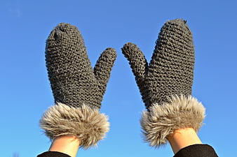 Gray Knitted Mittens with Fur Trim Against Blue Sky