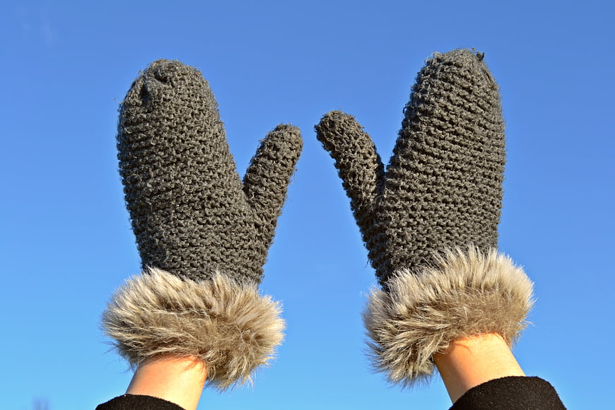 Gray Knitted Mittens with Fur Trim Against Blue Sky