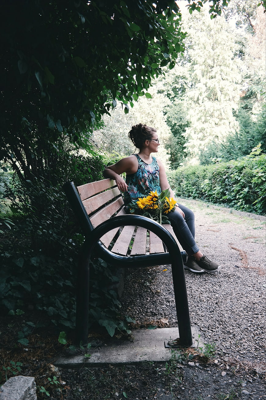 Woman with Sunflowers Sitting on Park Bench
