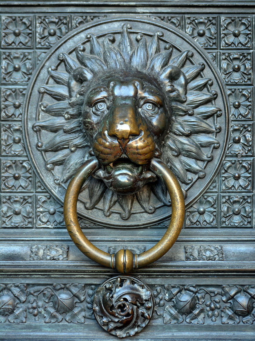 Close-up of ornate lion head brass door knocker on antique metal door