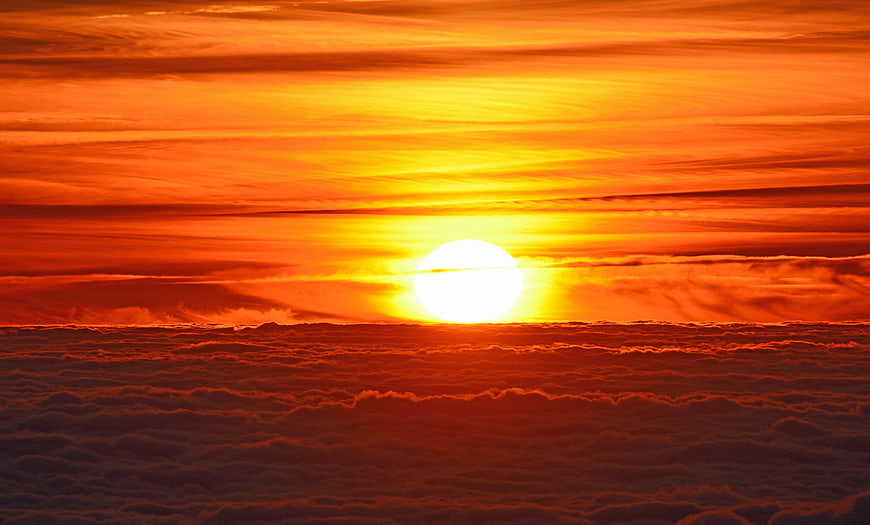 Vibrant orange sunset over a sea of clouds