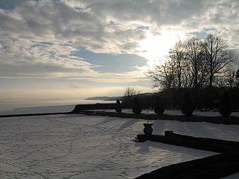 Snowy Winter Garden Landscape with Sunlit Sky and Lake View