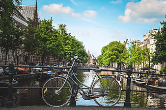 Bicycle Leaning On Canal Bridge Railing In Amsterdam