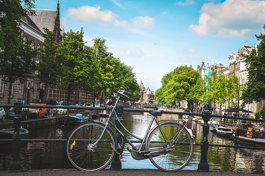 Bicycle Leaning On Canal Bridge Railing In Amsterdam
