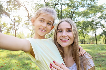 Happy mother and daughter taking selfie in sunny park
