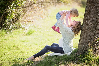 Pregnant mother playing with toddler daughter in sunny park