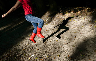 Woman in Red Boots Jumping in Forest with Shadow