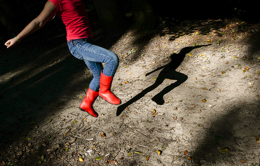 Woman in Red Boots Jumping in Forest with Shadow