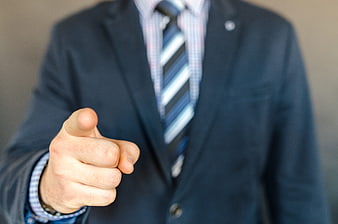 Businessman in dark suit pointing finger directly at camera