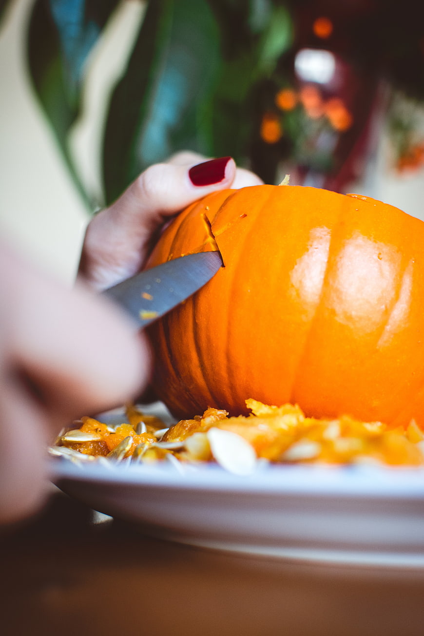Close-up of hands carving a bright orange pumpkin for Halloween