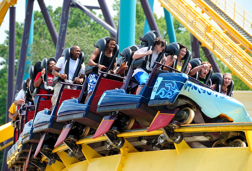 Excited Riders On A Blue And Red Roller Coaster Car