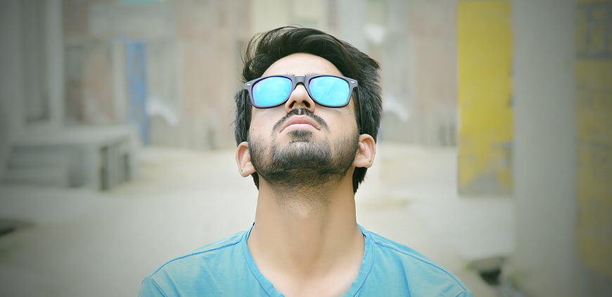 Young man with sunglasses looking up outdoors