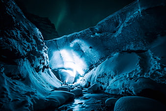 Blue Ice Cave Interior with Glowing Light and Snowy Rocks