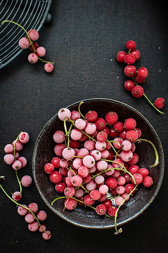 Top View of Frozen Red Currants in a Dark Ceramic Bowl
