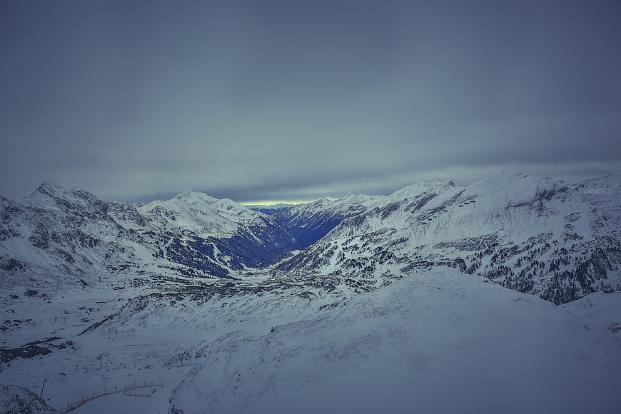 Snowy Mountain Landscape with Overcast Sky and Valley