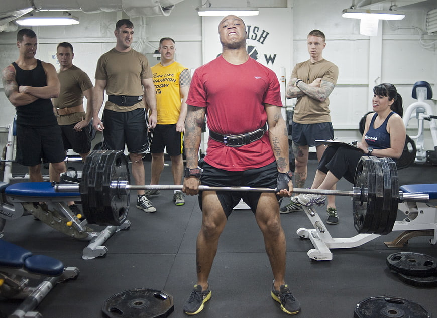 Athlete performing heavy deadlift in gym with observers