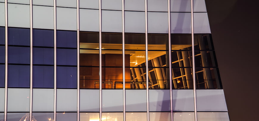 Modern glass building facade with warm interior lighting at night