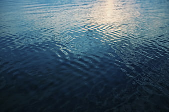 Calm blue water surface with gentle ripples and soft light reflection
