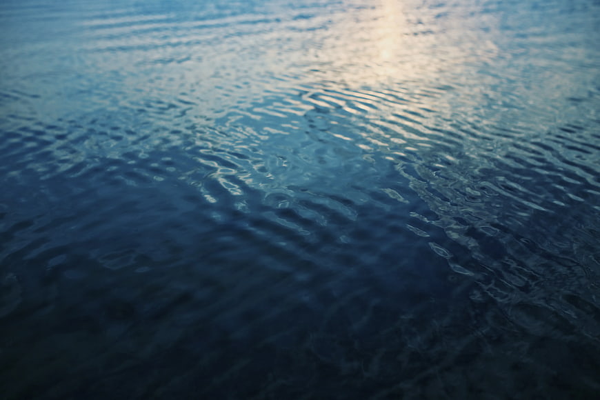 Calm blue water surface with gentle ripples and soft light reflection