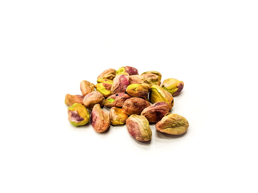 Pile of shelled pistachio nuts on white background