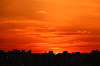 Vibrant orange sunset sky over city skyline silhouette