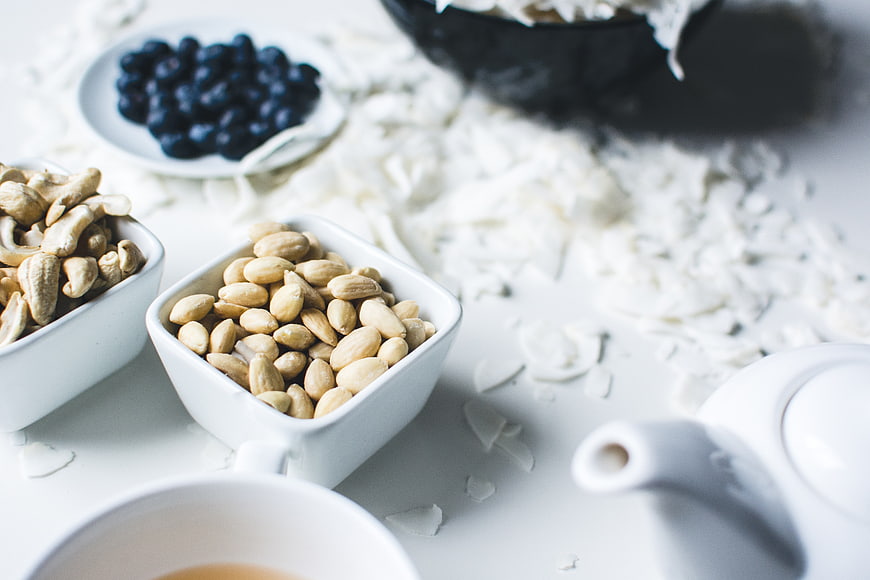 Healthy almonds, cashews, blueberries, and coconut flakes on white table
