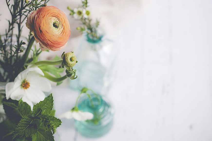 Fresh Orange Ranunculus and White Flowers in Blue Glass Vases