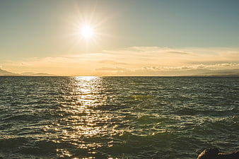 Sunlight reflecting on ocean waves with distant mountains