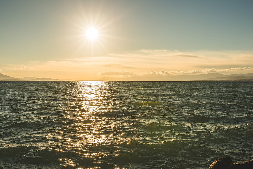 Sunlight reflecting on ocean waves with distant mountains