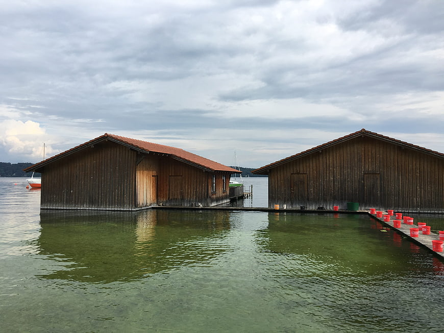 Traditional wooden boathouses on a calm lake under cloudy sky