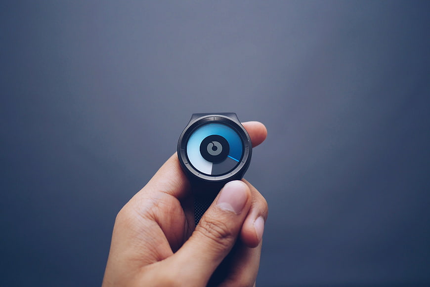Hand holding a modern smartwatch with a blue digital display