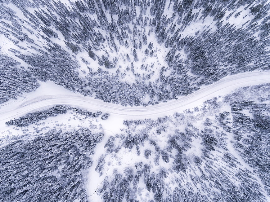 Aerial View of Snowy Forest and Winding Winter Road