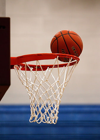 Basketball resting on orange rim and white net